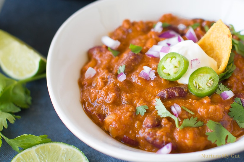 Instant Pot Chili Beans topped with sour cream, cilantro, red onion, lime wedge and chili slices