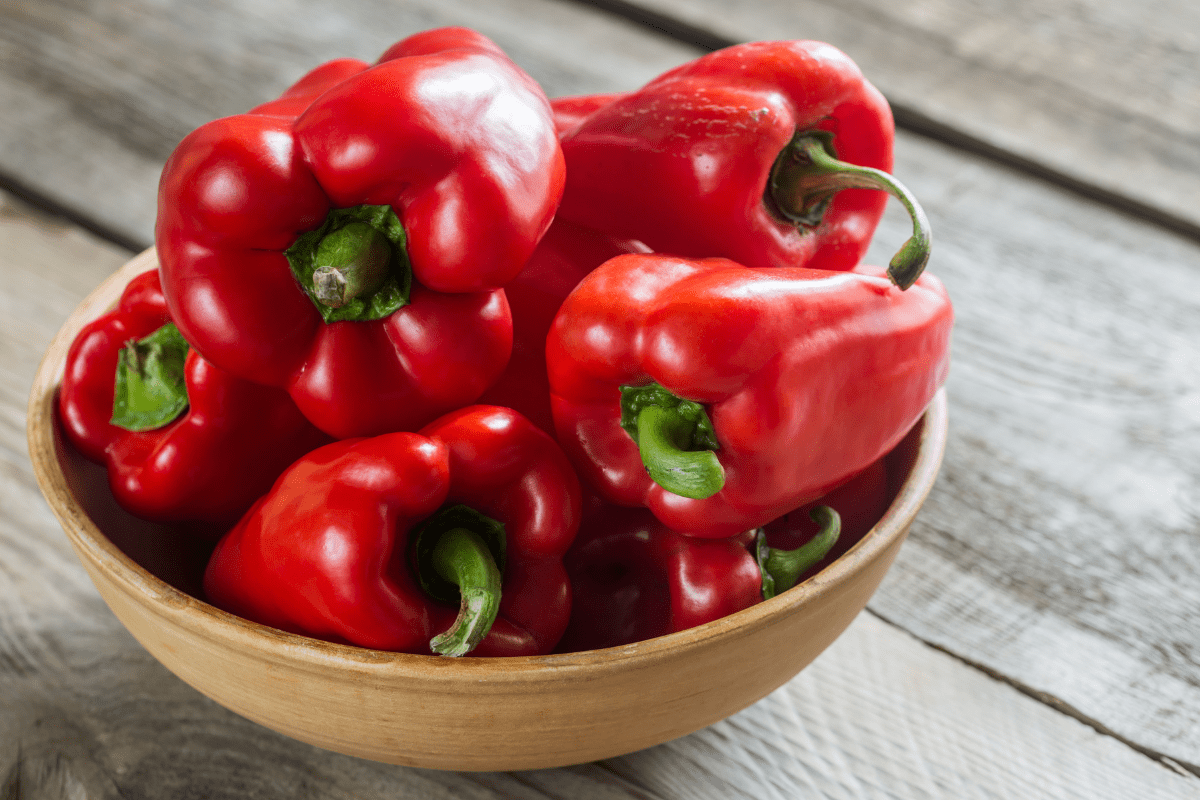 whole red bell peppers in bowl