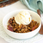gluten free peach crisp with vanilla bean ice cream in white bowl